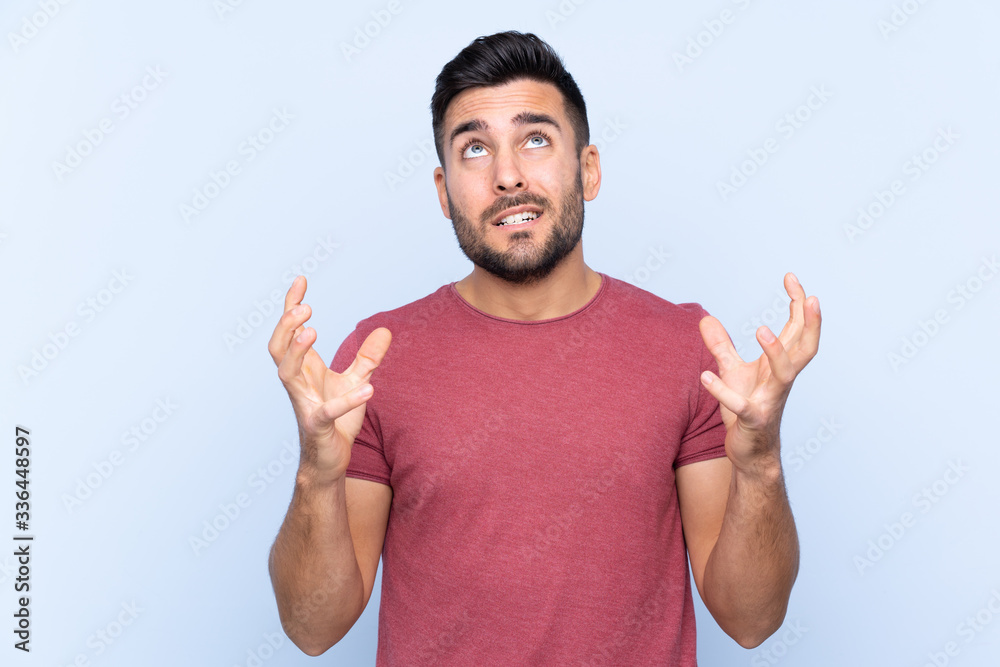 Young handsome man with beard over isolated blue background frustrated by a bad situation Young handsome man with beard over isolated blue background frustrated by a bad situation