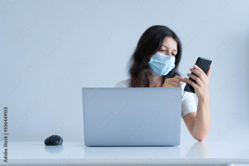 The girl works from home during quarantine. Corona virus pandemic. A girl in a surgical mask works on a laptop and drinks coffee. Distant work The girl works from home during quarantine. Corona virus pandemic. A girl in a surgical mask works on a laptop and drinks coffee. Distant work