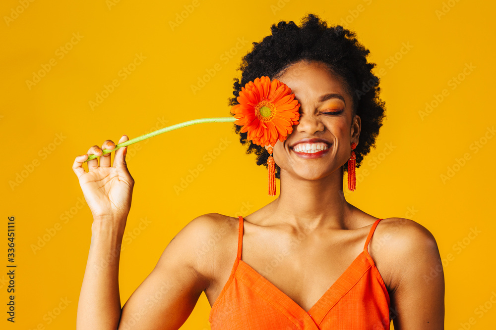 Portrait of a happy young woman holding orange Gerbera daisy covering her  eye with eyes closed Stock Photo | Adobe Stock