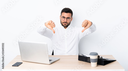Young businessman in a workplace showing thumb down