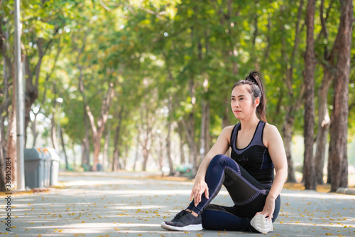 Portrait of Asian woman wearing black sports bra for exercising by running in public park. Urban health care concept. © amornchaijj