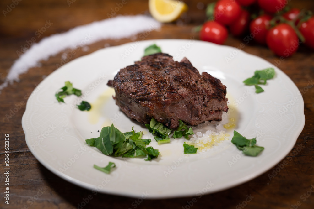 grilled beef fillet with rocket, extra virgin olive oil, salt and black pepper on the wooden table of an old tavern