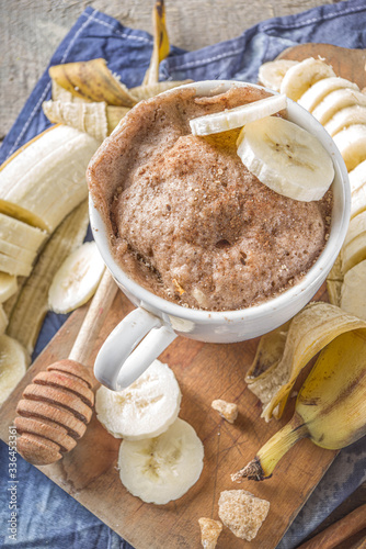 Portioned Banana bread mugcake in small mugs. Easy sweet baking idea, With fresh bananas, nuts, honey and spices on rustic wooden background copy space photo