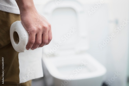 Foto man diarrhea holds toilet paper roll in front of toilet bowl.