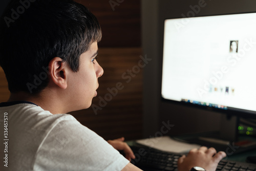Teenager concentrated is studying at home attending online classes during the coronavirus COVID-19 pandemic quarantine