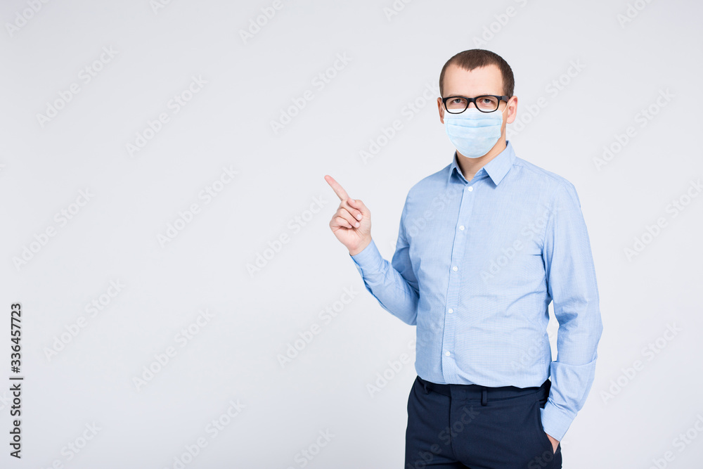 coronavirus, pandemic, quarantine and health care concept - portrait of young businessman in medical mask pointing at something over gray background coronavirus, pandemic, quarantine and health care concept - portrait of young businessman in medical mask pointing at something over gray background