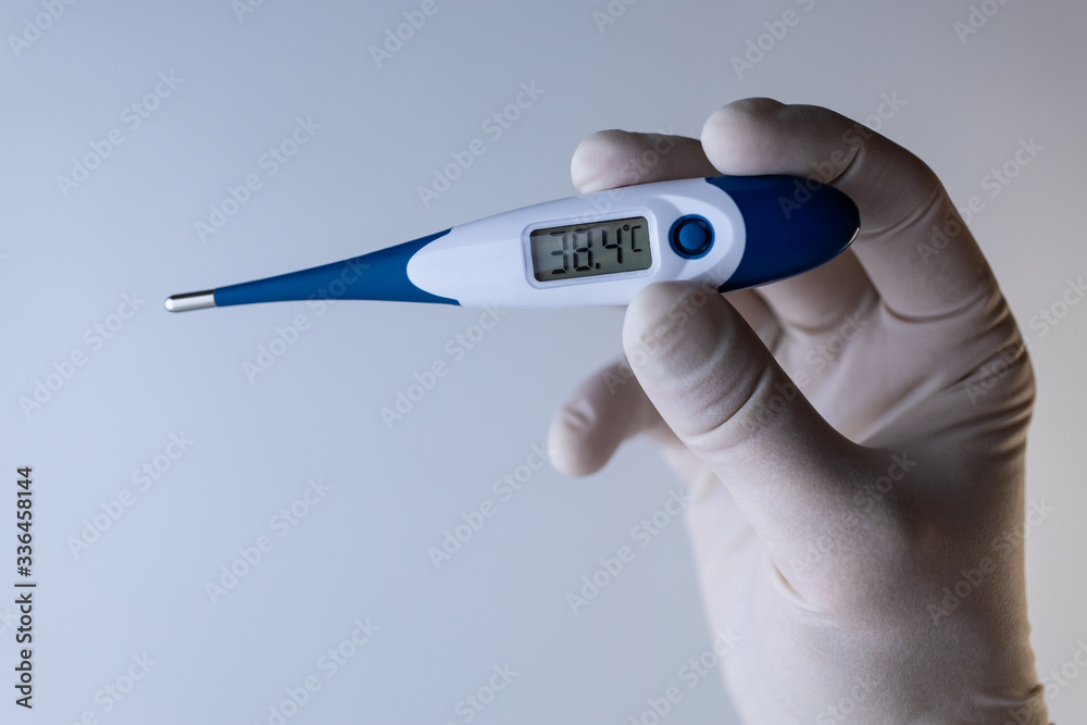 Obraz premium Hand in a medical glove holds a thermometer.