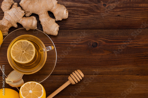 Cup of Ginger tea with lemon, honey and ginger root on a wooden background with copy space, top view