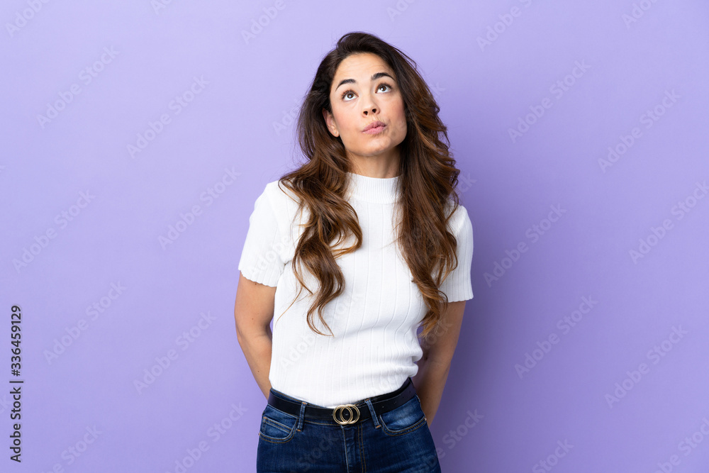 Woman over isolated purple background and looking up Woman over isolated purple background and looking up