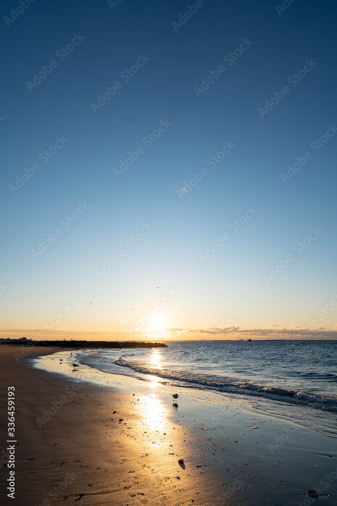 Sunrise over Atlantic Ocean, blue sky, piers. Pier and blue Atlantic Ocean. Red sky sun beams. 