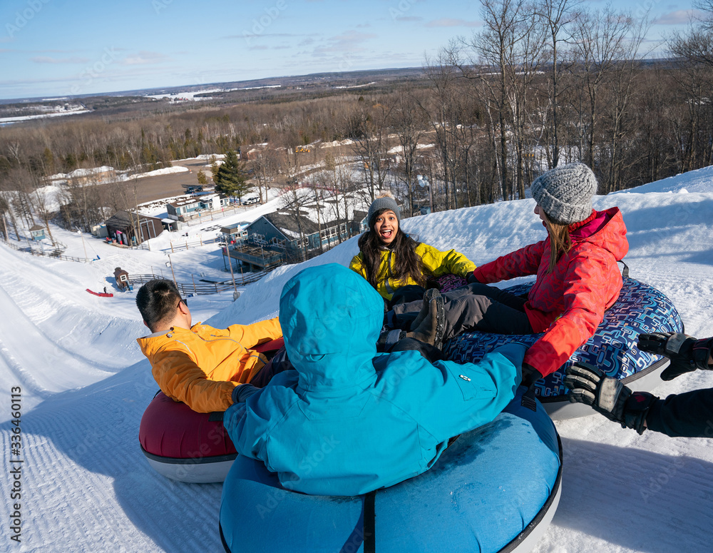 Group of multiracial millenials snow tubing in the winter in Canada with an active lifestyle