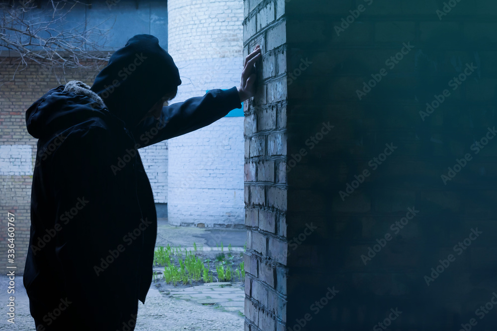 Silhouette of a man standing against a wall. The fight against crime and drug addiction. Social problems. Silhouette of a man standing against a wall. The fight against crime and drug addiction. Social problems.