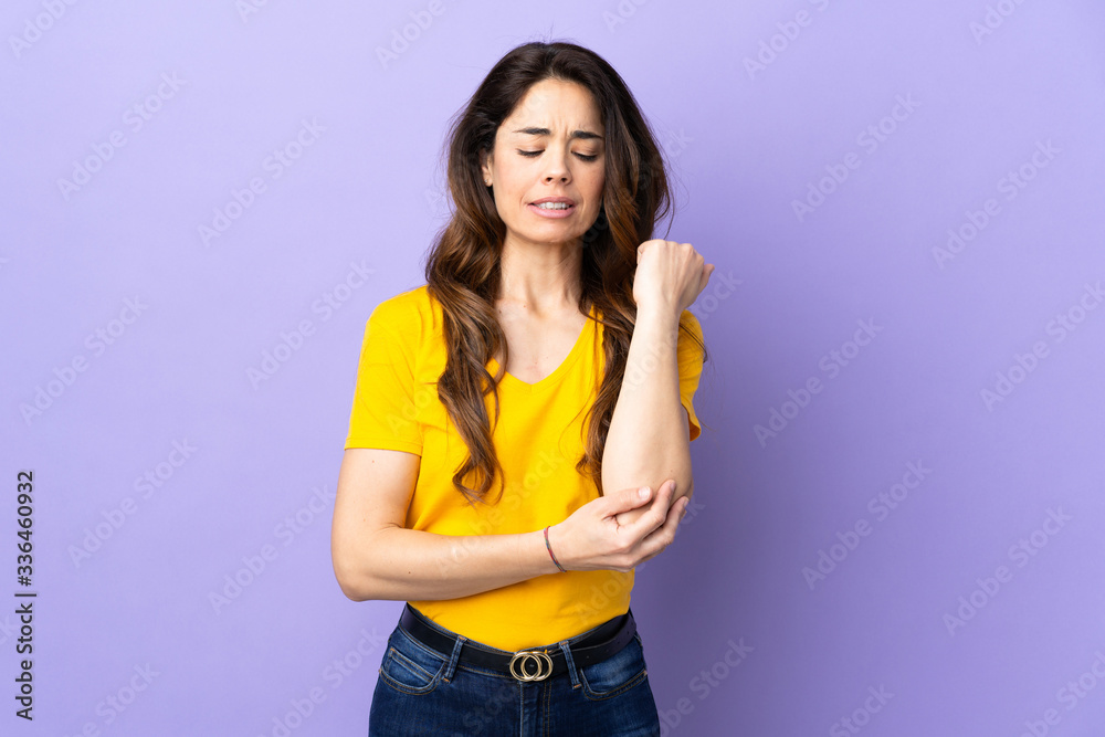 Woman over isolated purple background with pain in elbow Woman over isolated purple background with pain in elbow