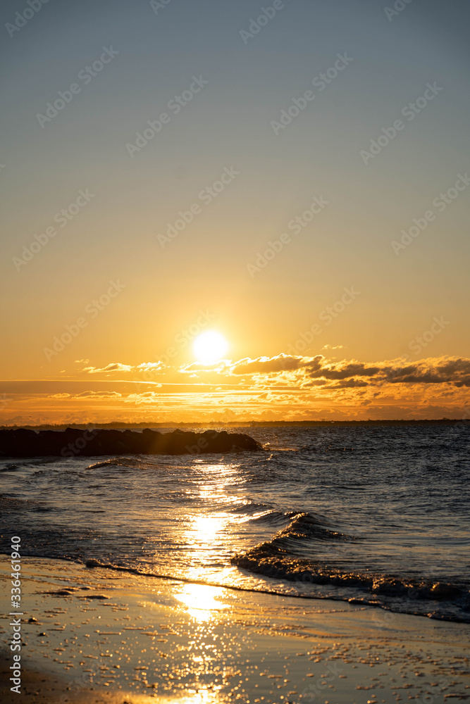 Naklejka premium Sunrise over Atlantic Ocean with a red sky and red sunbeams and blue ocean water. 
