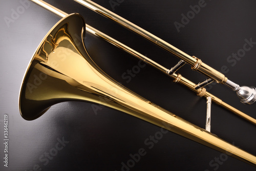 Принти на полотні Golden trombone detail on a black wooden table
