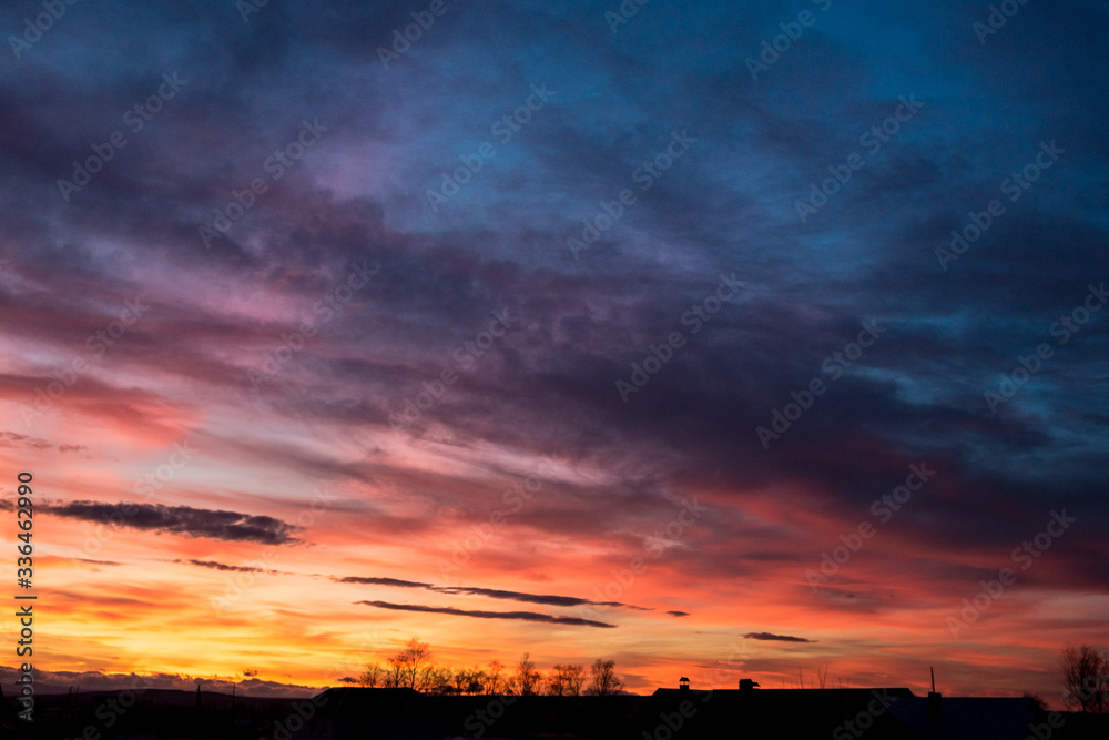 Sunset. Evening sky, clouds are painted in different bright colors: blue, red, orange, purple, pink, yellow.
