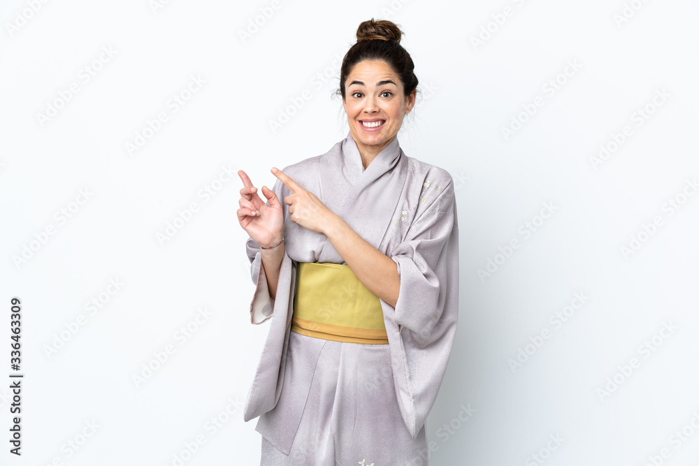 Woman wearing kimono over isolated background frightened and pointing to the side Woman wearing kimono over isolated background frightened and pointing to the side