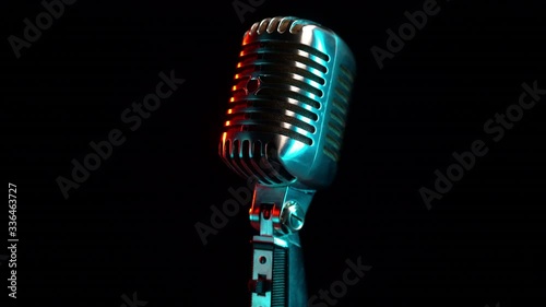 Retro microphone rotating on black background with teal orange light