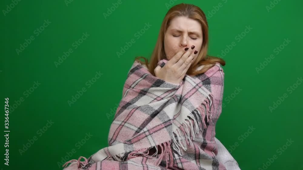 Sick woman wrapped in warm blanket drinking hot tea. Cough. Coughing. Sore throat. COVID Danger of coronavirus pandemic 2019-ncov. Shot on a green isolated background. Quarantine, fears. Chromakey. Sick woman wrapped in warm blanket drinking hot tea. Cough. Coughing. Sore throat. COVID Danger of coronavirus pandemic 2019-ncov. Shot on a green isolated background. Quarantine, fears. Chromakey.