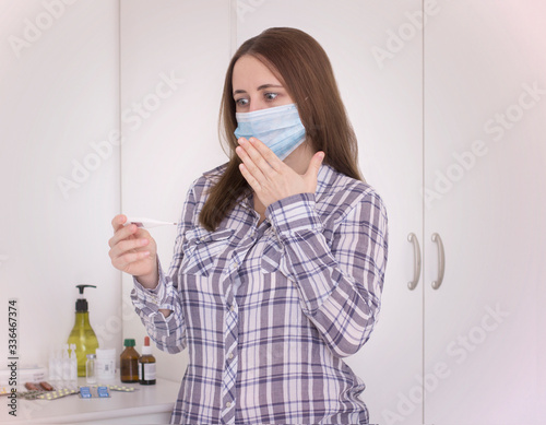 girl in a mask with a thermometer in her hands