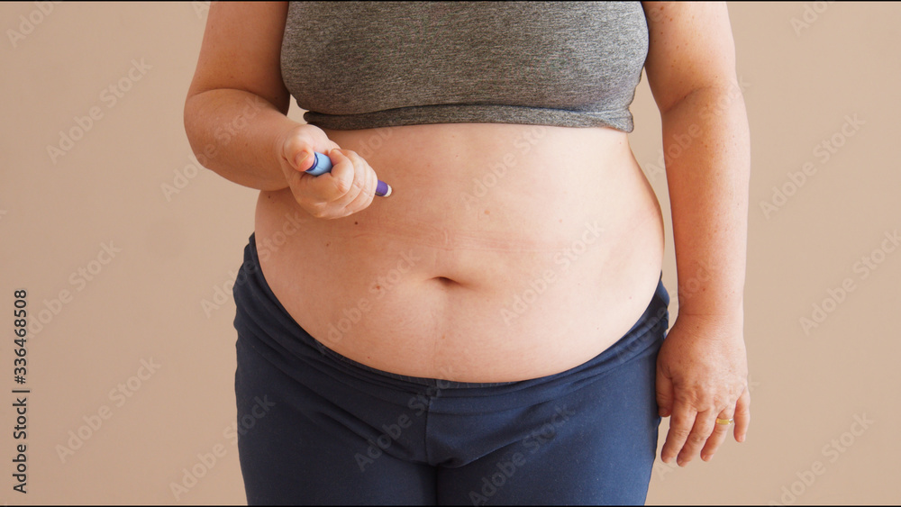 Overweight woman applying diabetes medicine injection into her stomach