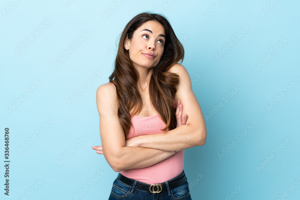 Woman over isolated blue background making doubts gesture while lifting the shoulders Woman over isolated blue background making doubts gesture while lifting the shoulders