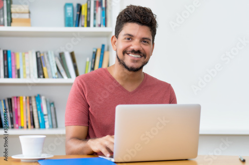 Handsome latin american man with beard working at computer