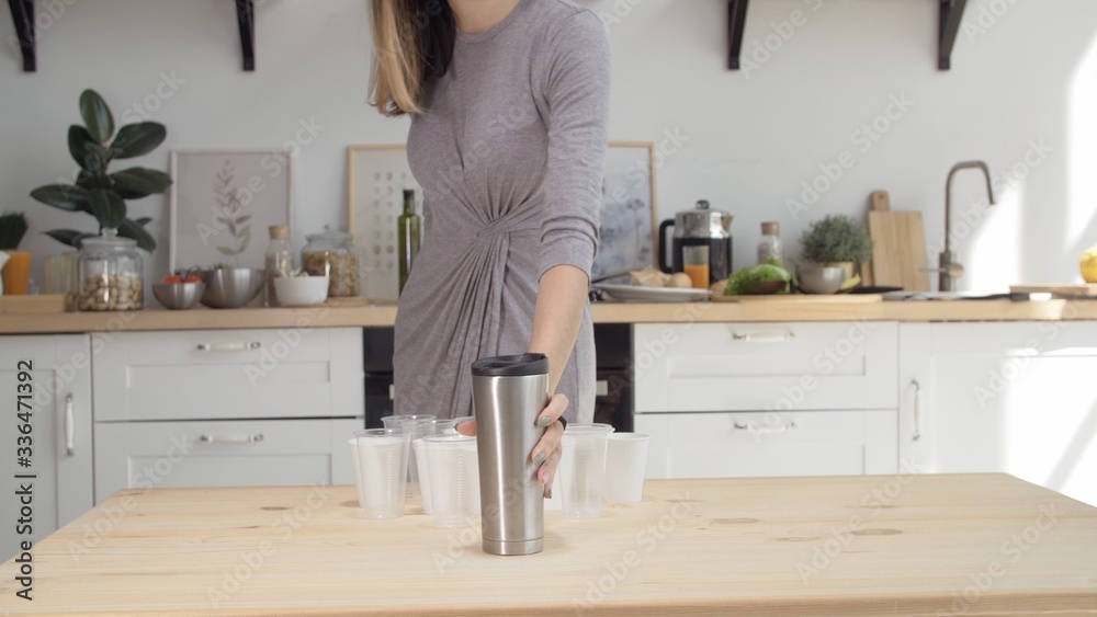 Girl refuses of disposable cup in favor of reusable thermos, plastic pollution. Woman puts a reusable thermos on the table. The concept of reusable utensils. Fight for the environment. Girl refuses of disposable cup in favor of reusable thermos, plastic pollution. Woman puts a reusable thermos on the table. The concept of reusable utensils. Fight for the environment.