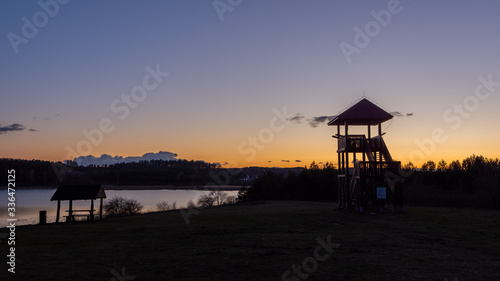 Fototapeta Naklejka Na Ścianę i Meble -  Wieża widokowa nad jeziorem na tle zachodzącego słońca. Warmia i Mazury. Polska