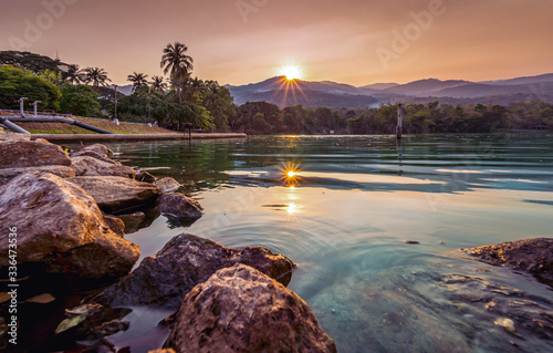 Beautiful sunset at lake in Chiang Mai University with Doi Suthep mountain in background. AngKaew Lake and traveler couple in Chiang Mai University