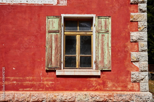 Fenster mit Fensterladen an einer roten Fassade