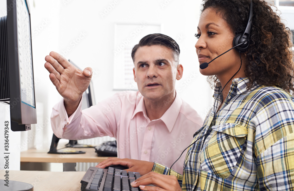 Fototapeta premium Businessman Training Female Employee Wearing Headset In Call Centre Office