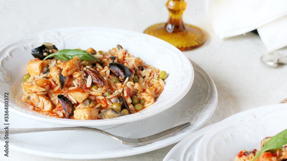paella from orzo pasta with mussels, seashells and chicken. Seafood paella, traditional spanish dish. Paella on rustic black wooden table. Top view paella from orzo pasta with mussels, seashells and chicken. Seafood paella, traditional spanish dish. Paella on rustic black wooden table. Top view