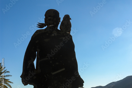 Silueta de pirata de espalda con el loro en el hombro con cielo azul