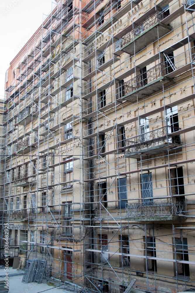 Fototapeta premium Tall building under construction with scaffolds. Scaffold. Construction Scaffoldings
