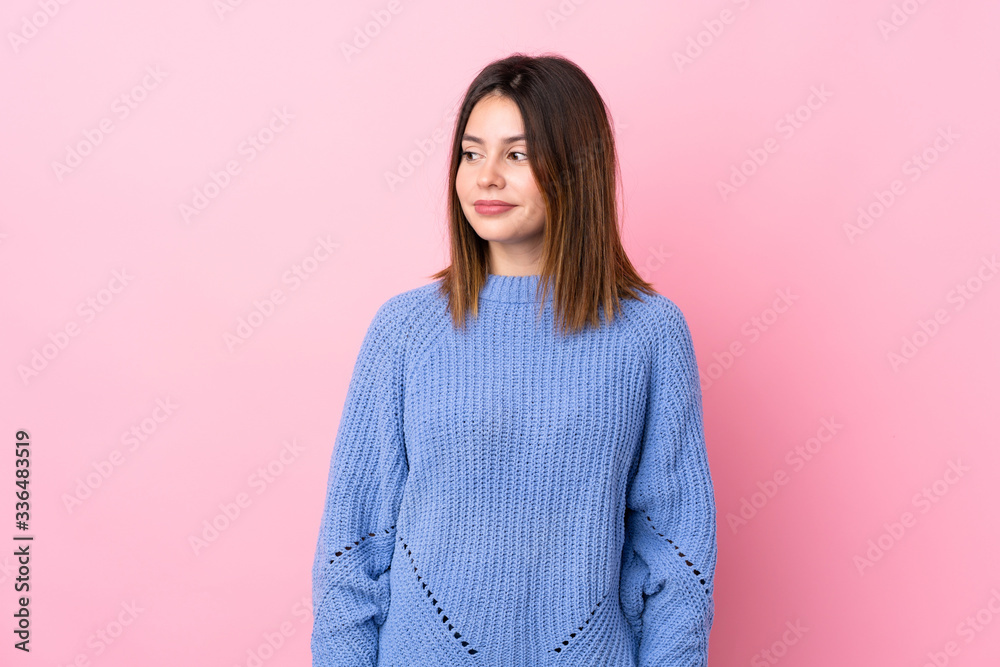 Young woman with blue sweater over isolated pink background standing and looking to the side Young woman with blue sweater over isolated pink background standing and looking to the side
