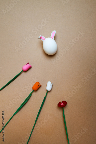 easter bunny made from chikern egg with wooden flowers on craft paper background, sping at home and easter at home concept