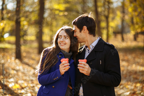 guy with a girl drink coffee in a park. Autumn in the park. sunny day
