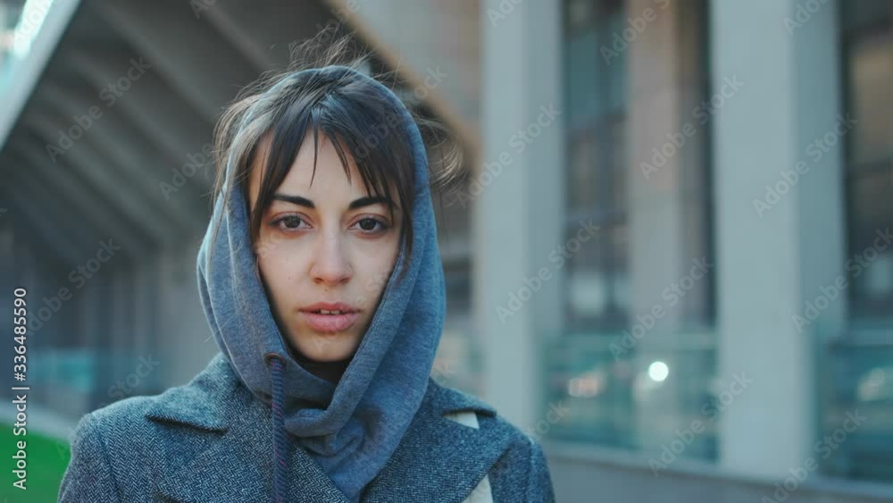 closeup front view attractive caucasian woman tourist in hoody standing european city looking straight confidently. 4k shot female on urban background outdoors closeup front view attractive caucasian woman tourist in hoody standing european city looking straight confidently. 4k shot female on urban background outdoors