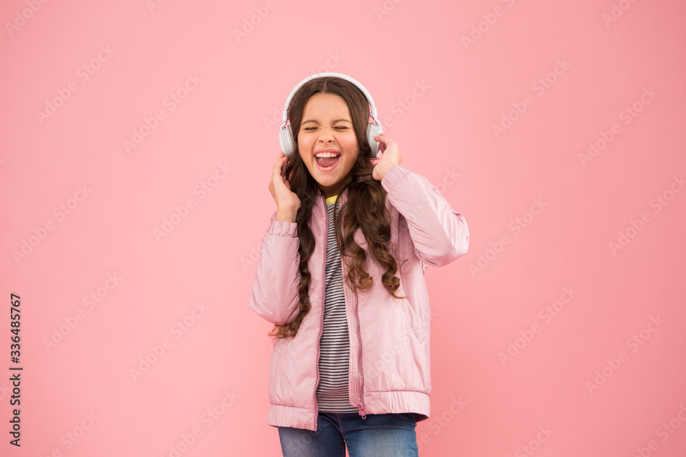 full of emotions. Little child do vocal on song. Emotional singer. Enjoying song playing in headphones. Karaoke and entertainment. Joining in a song. Small girl sing to song pink background