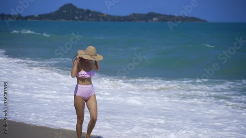 Wallpaper Mural A girl walks along the ocean and looks at the waves. A girl in sunglasses and a pink bathing suit. Lamai beach on Koh Samui Torontodigital.ca