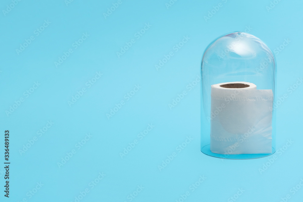 Half roll of toilet paper in quarantine under a glass cloche dome on a blue background with copy space and room for text with a right side composition.