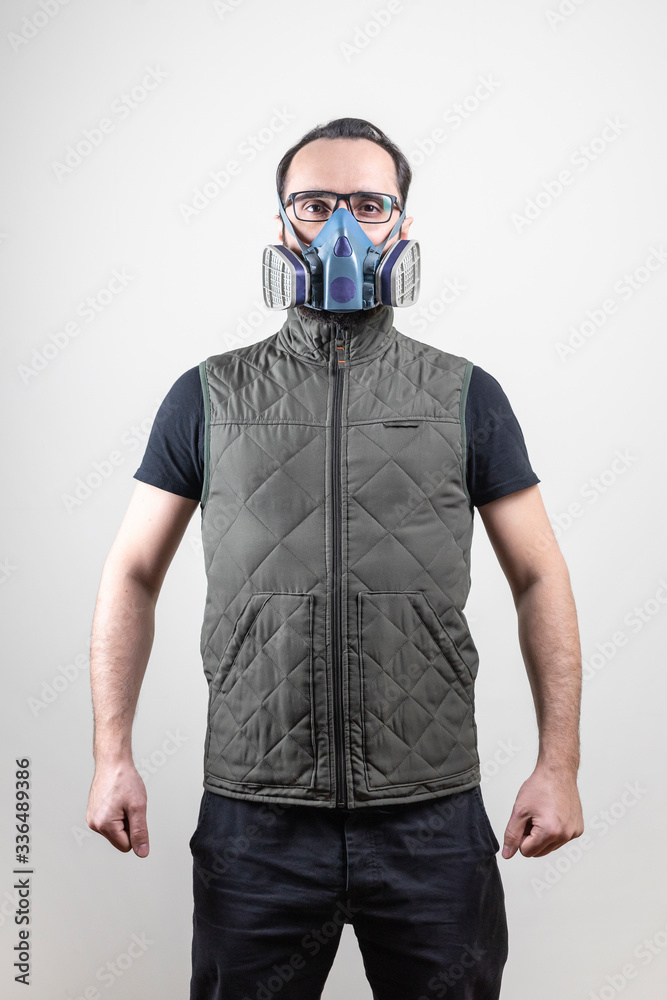man in a protective mask stands in a pose on a gray isolated background. Epidemic, quarantine, outbreak of Covid-19 coronavirus disease. Specialized infection protection
