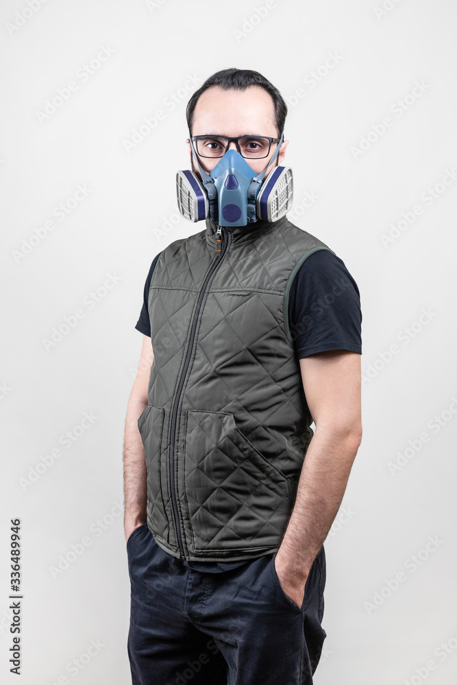 man on an isolated gray background stand a mask to protect against gases and viruses. man on an isolated gray background stand a mask to protect against gases and viruses.