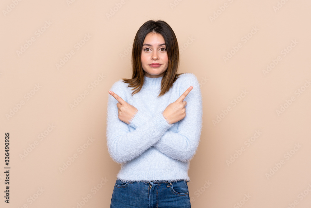 Young woman over isolated background pointing to the laterals having doubts Young woman over isolated background pointing to the laterals having doubts