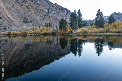 reflecctive mountain lake with pines aspens grass and mountain