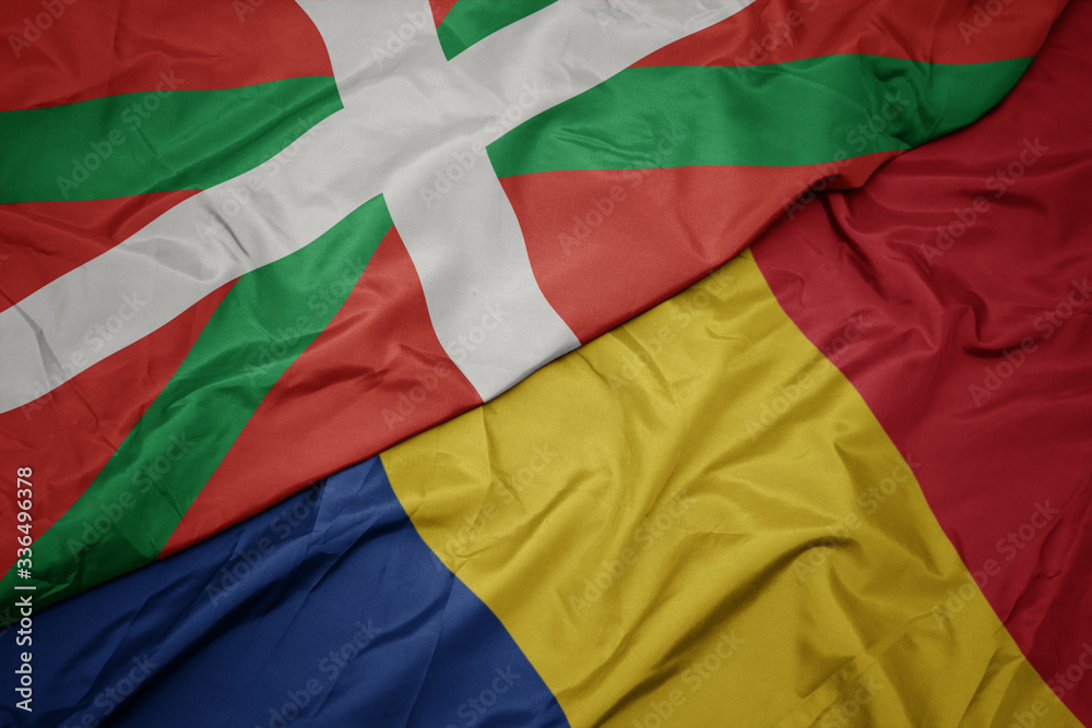 waving colorful flag of romania and national flag of basque country.
