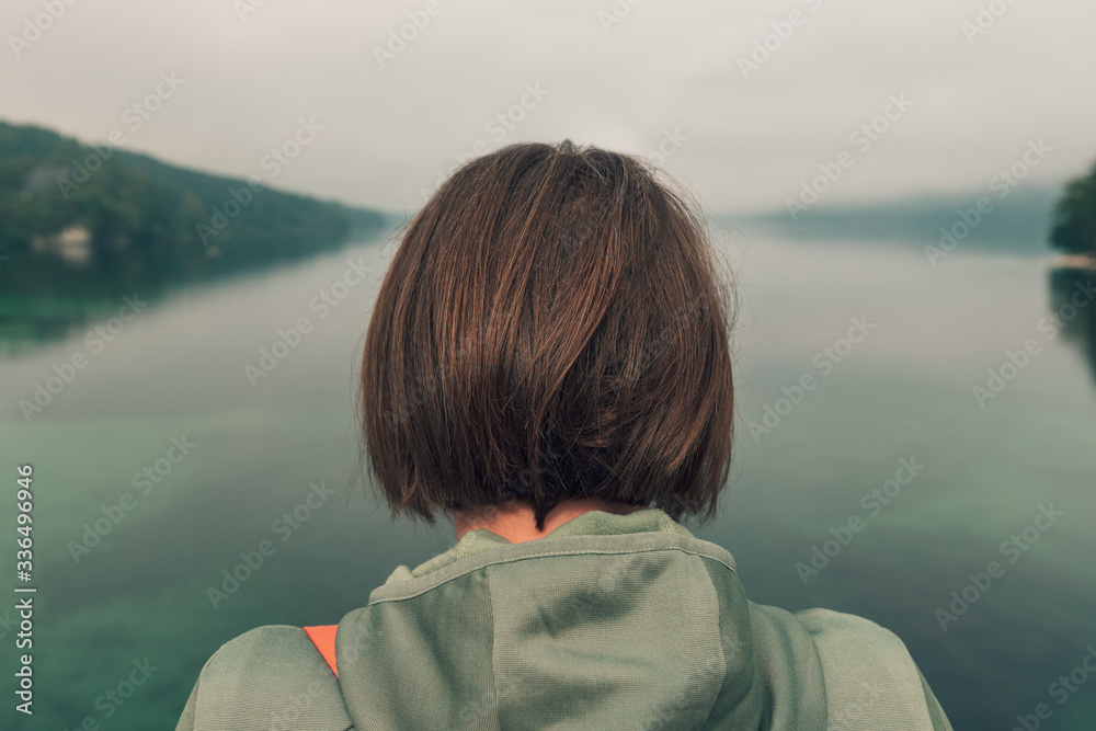 Female hiker standing on bridge and looking over lake Female hiker standing on bridge and looking over lake