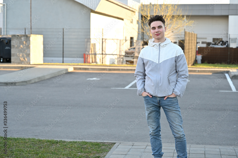 Portrait of a Caucasian young brunette man in a light jacket outdoors on a city-background. Portrait of a Caucasian young brunette man in a light jacket outdoors on a city-background.