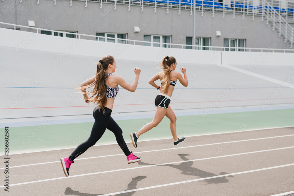 Running and fitness. Young beautiful fit women with perfect bodies in sportswear run outdoors on the track. Sportive and healthy lifestyle, working out, training, fashion, beauty concept.